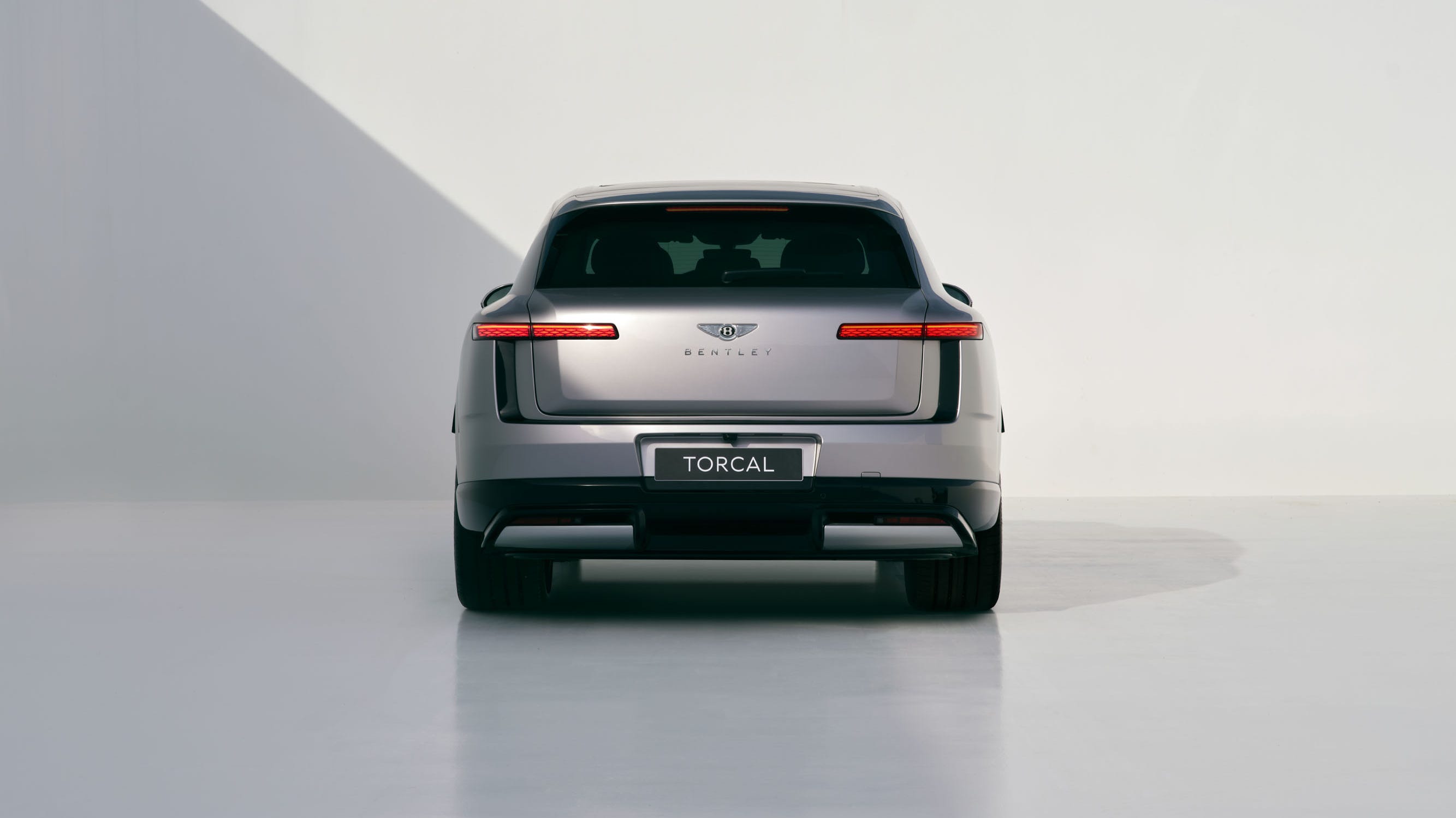 A sleek silver Bentley SUV with distinctive rear lights against a minimalist background.