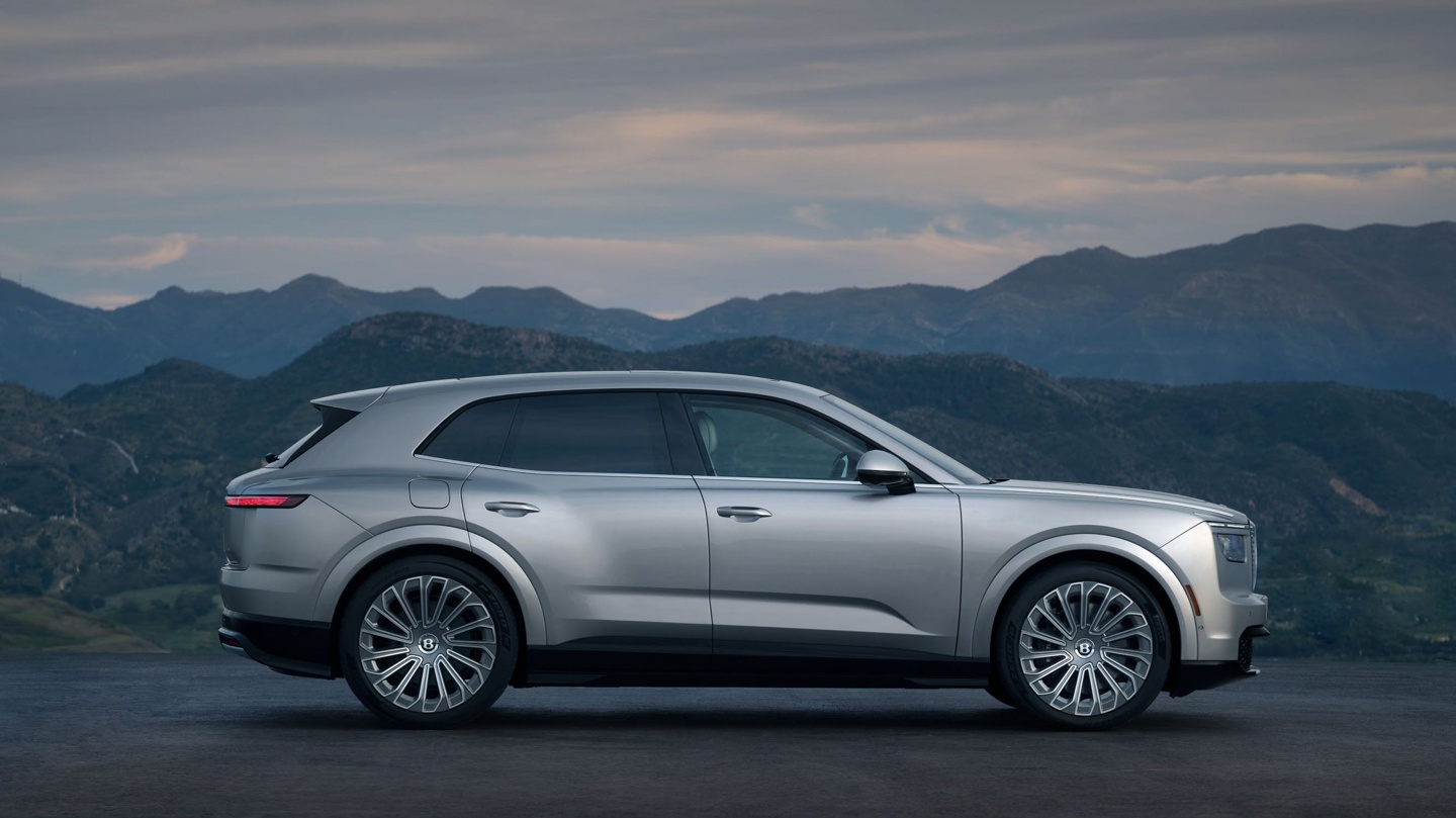 A sleek silver SUV parked against a backdrop of mountains under a dramatic sky.